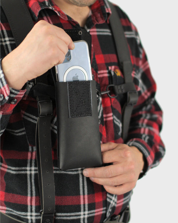A person wearing a plaid shirt and a black belt designed to hold a mobile phone, with the phone partially visible in the image.